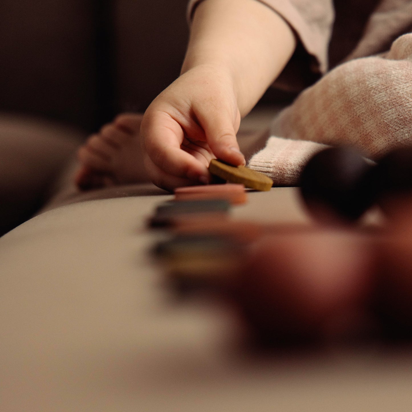 Montessori-inspired wooden pegboard toy in Natural Oak with Earth Palette by Woodsie Wonder, shown in close-up play detail with a child’s hand.