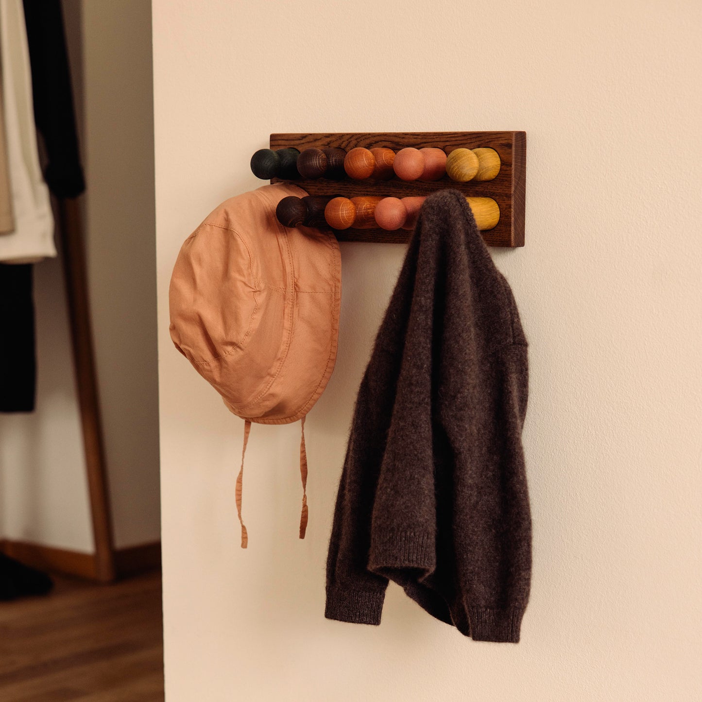Wooden children’s wall coat rack and sorting toy in one by Woodsie Wonder – Play & Hang in Brown Oak with Earth Palette, designed as a sorting toy that transforms into playful wall storage.