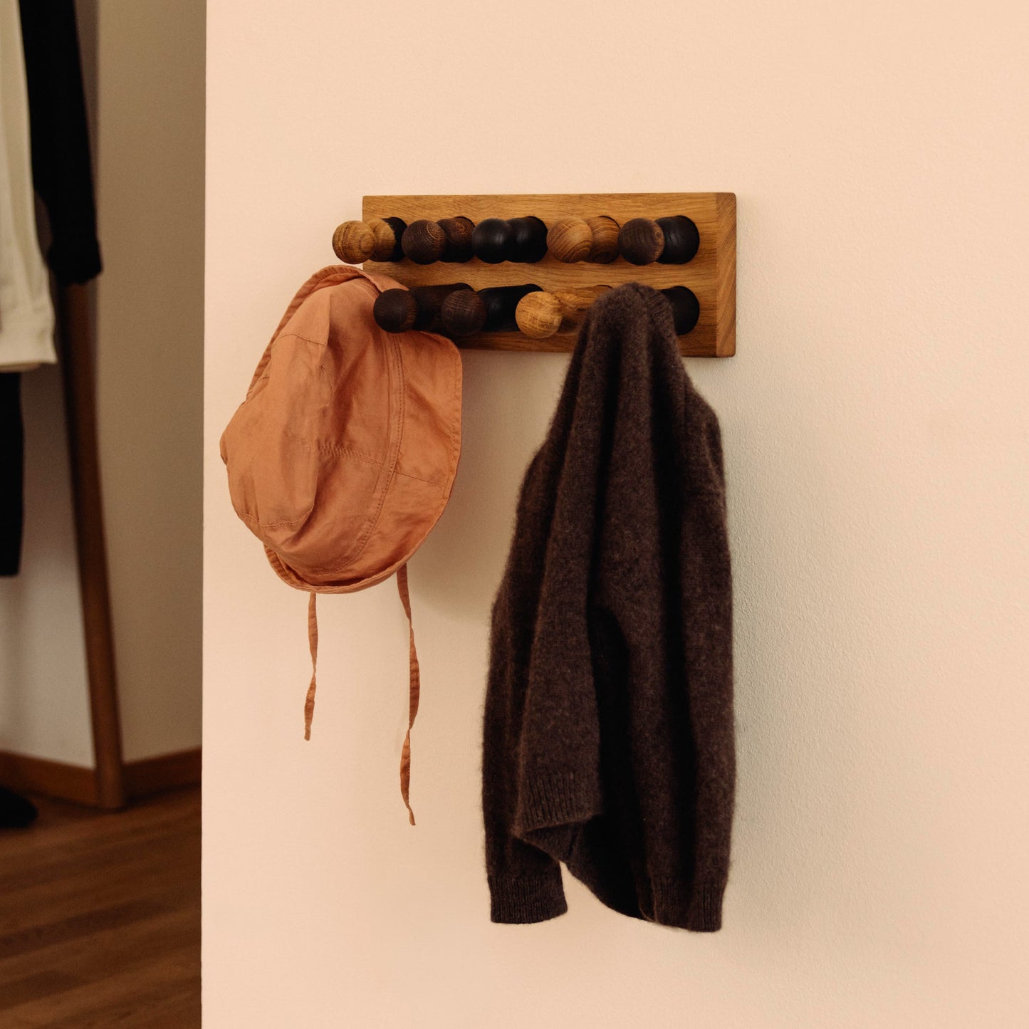 Wooden children’s wall coat rack and sorting toy in one by Woodsie Wonder – Play & Hang in Natural Oak with Mono Palette, designed as a sorting toy that transforms into playful wall storage.