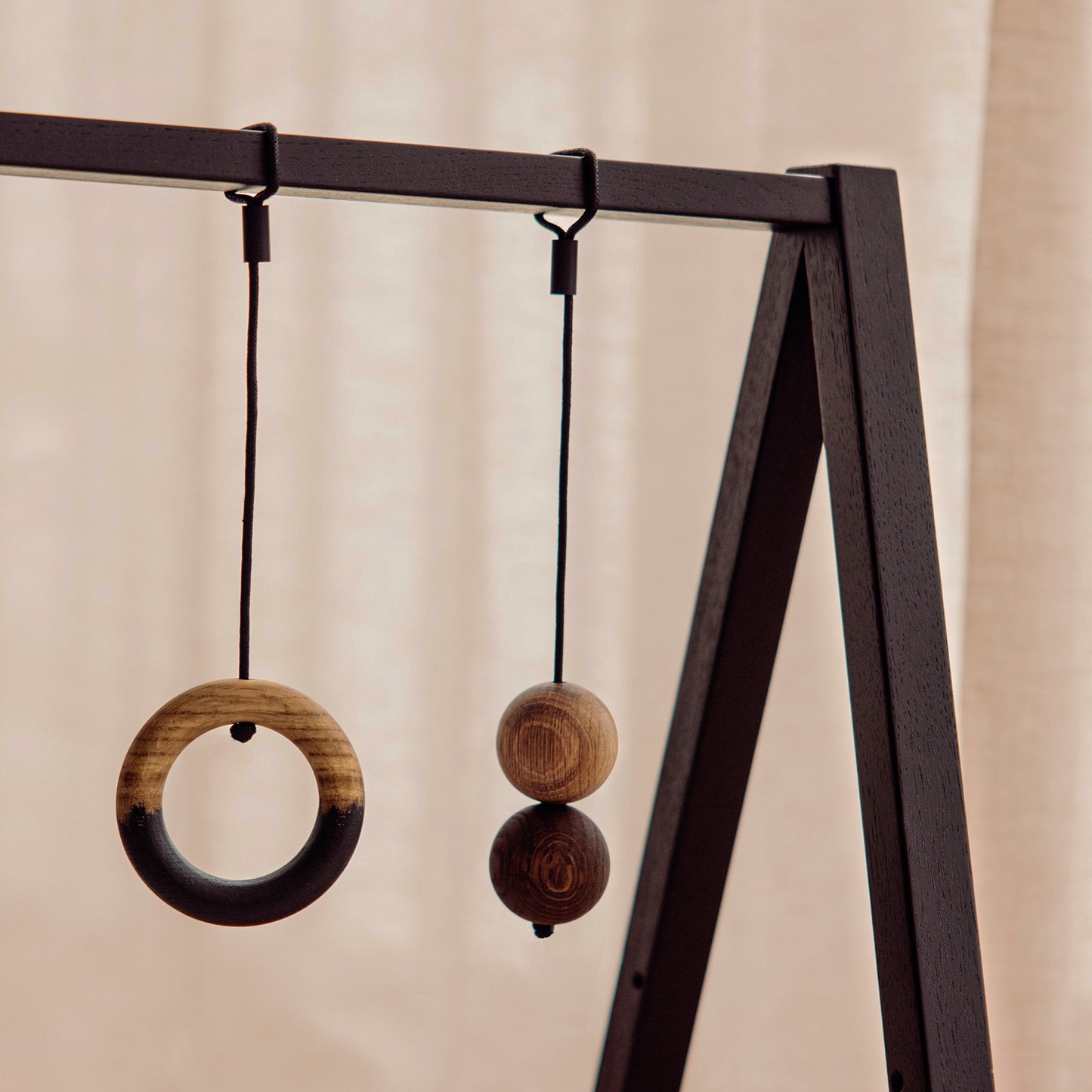 Wooden play gym hanging toys made of FSC-certified solid oak. Play & Read in Black Oak with Mono Palette by Woodsie Wonder.