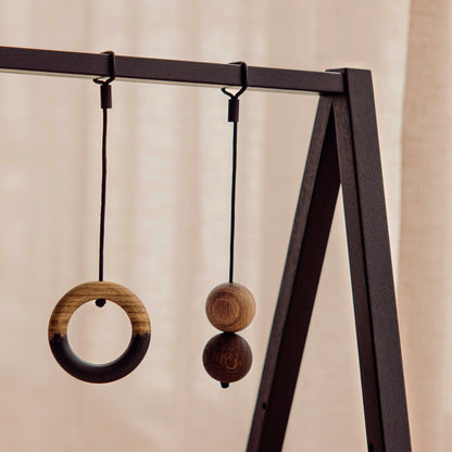 Wooden play gym hanging toys made of FSC-certified solid oak. Play & Read in Black Oak with Mono Palette by Woodsie Wonder.