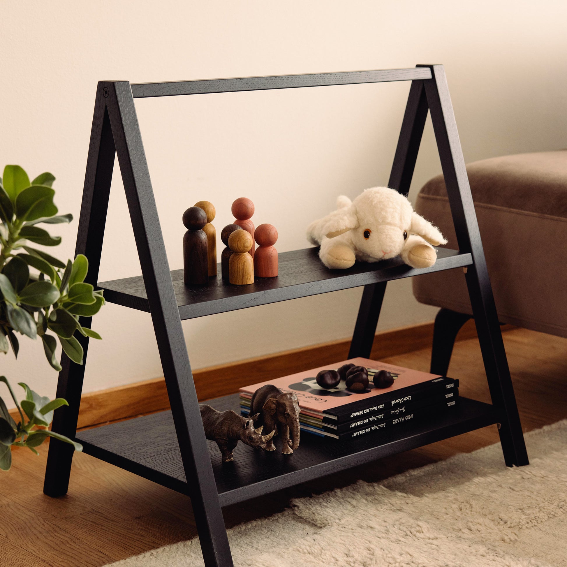 Wooden kids' book and toy shelf in a living room setting, made of FSC-certified solid oak. Play & Read in Black Oak by Woodsie Wonder.