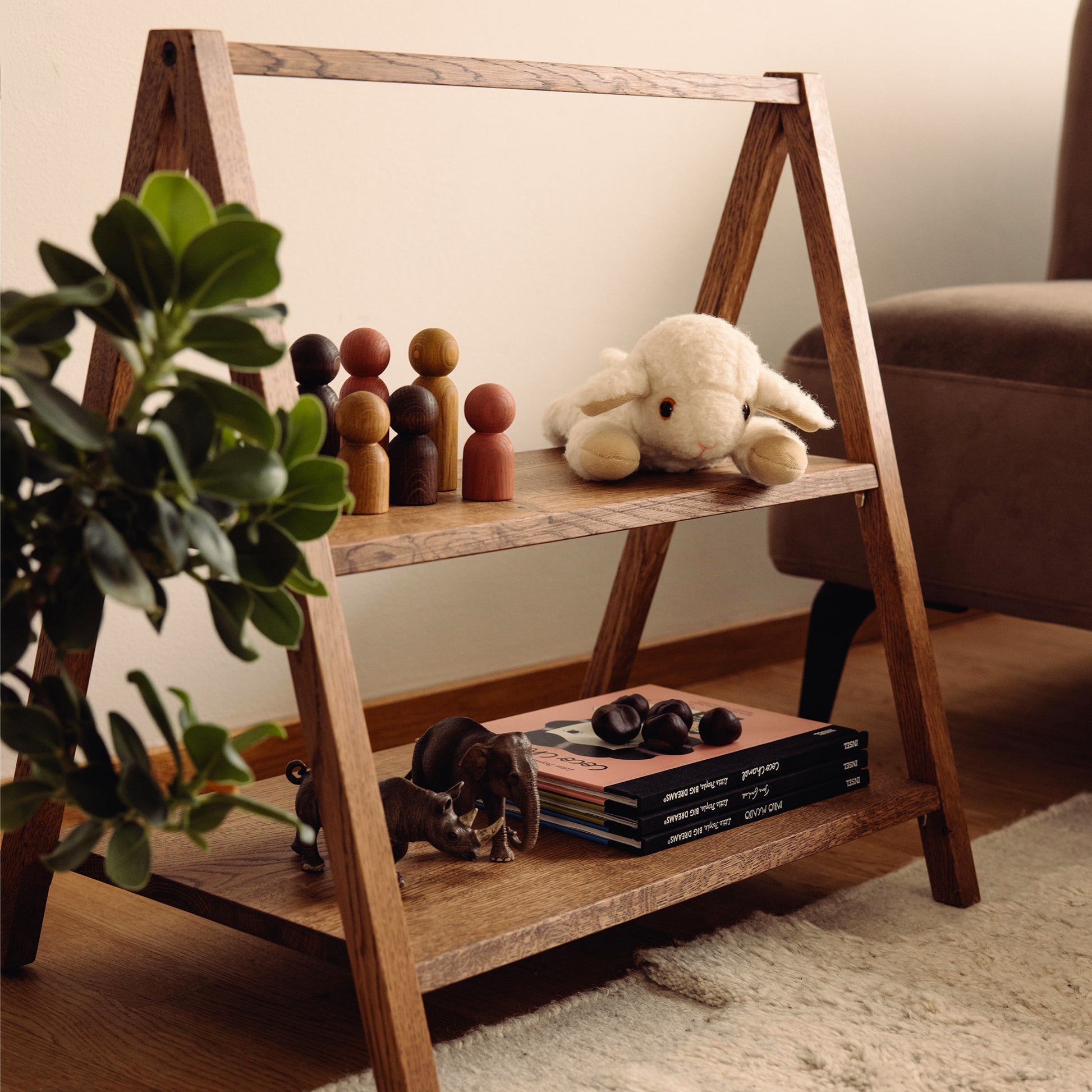 Wooden kids' book and toy shelf in a living room setting, made of FSC-certified solid oak. Play & Read in Brown Oak by Woodsie Wonder.