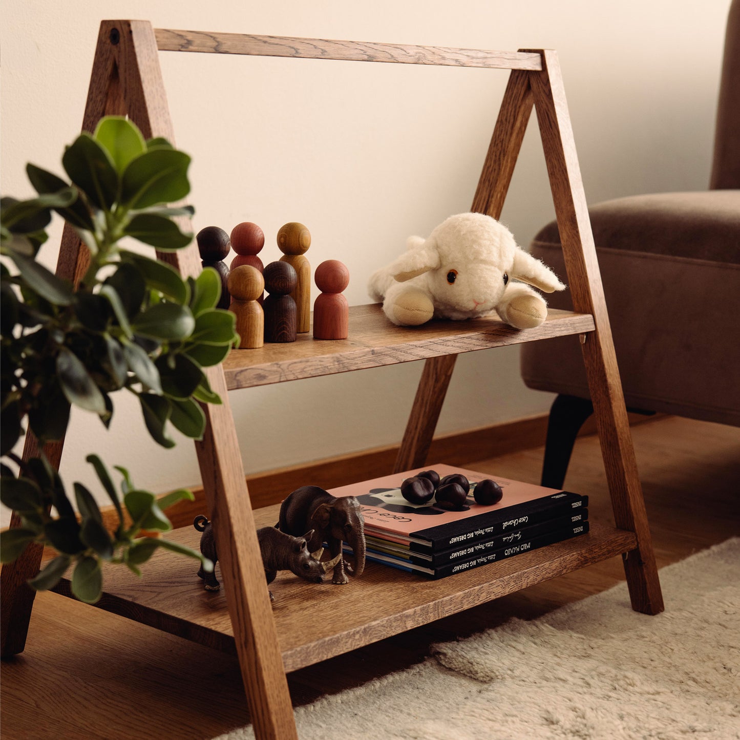 Wooden kids' book and toy shelf in a living room setting, made of FSC-certified solid oak. Play & Read in Brown Oak by Woodsie Wonder.