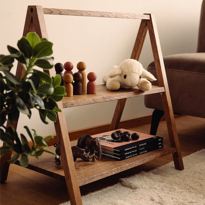 Wooden kids' book and toy shelf in a living room setting, made of FSC-certified solid oak. Play & Read in Brown Oak by Woodsie Wonder.