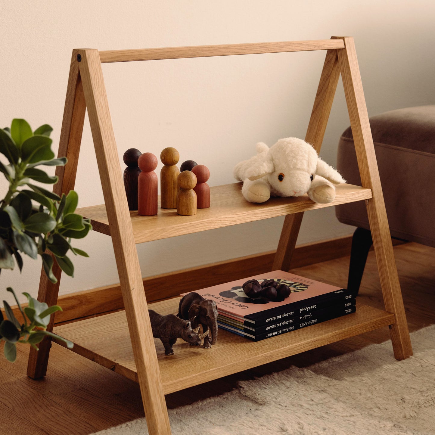 Wooden kids' book and toy shelf in a living room setting, made of FSC-certified solid oak. Play & Read in Natural Oak by Woodsie Wonder.