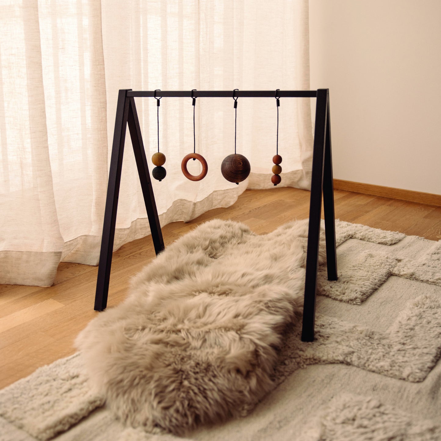 Wooden baby play gym with hanging toys that transforms into elegant bookshelf. Play & Read in Black Oak with Earth Palette by Woodsie Wonder.