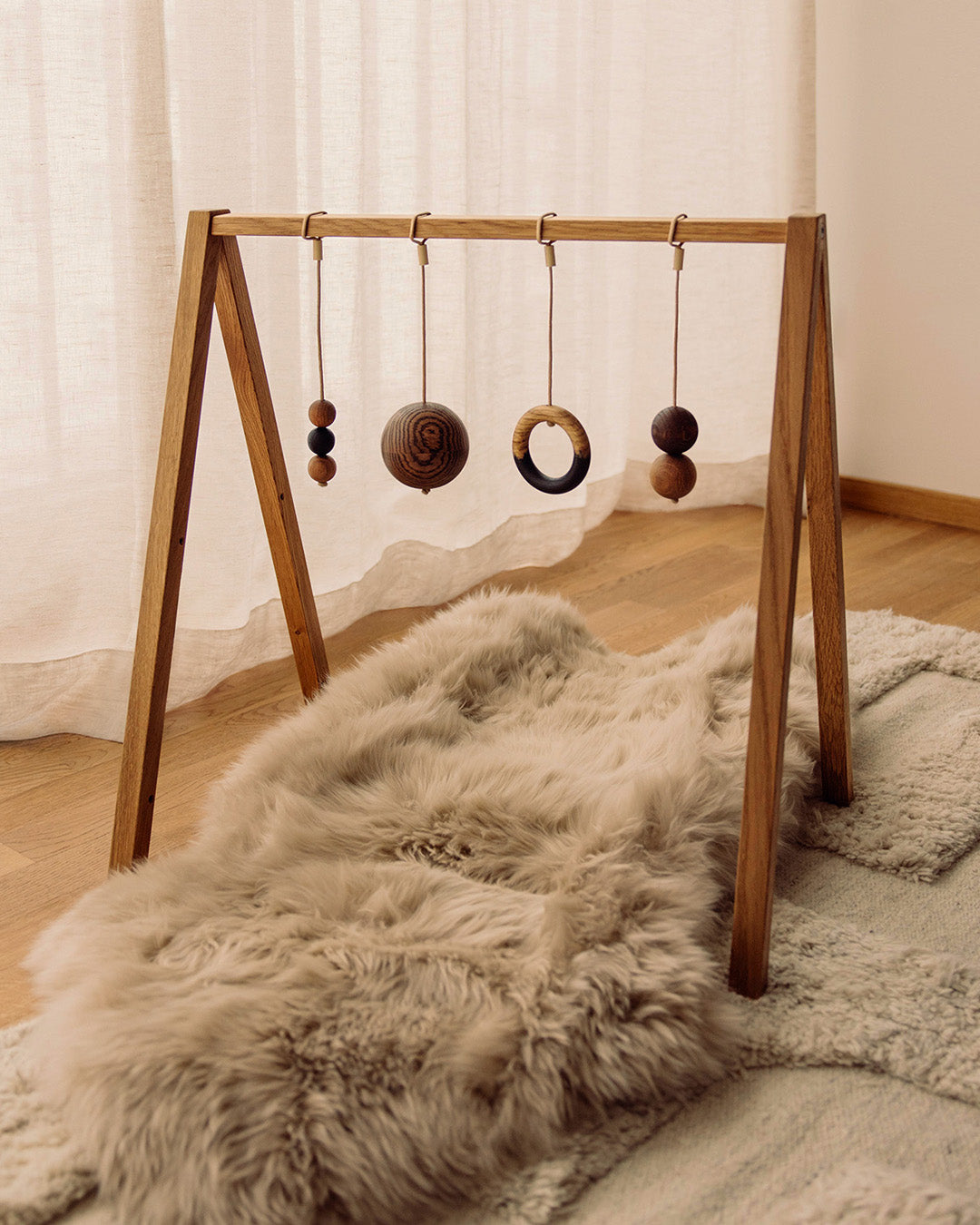 Play & Read wooden baby gym in Natural Oak with the Mono Palette, shown in a cosy family interior.