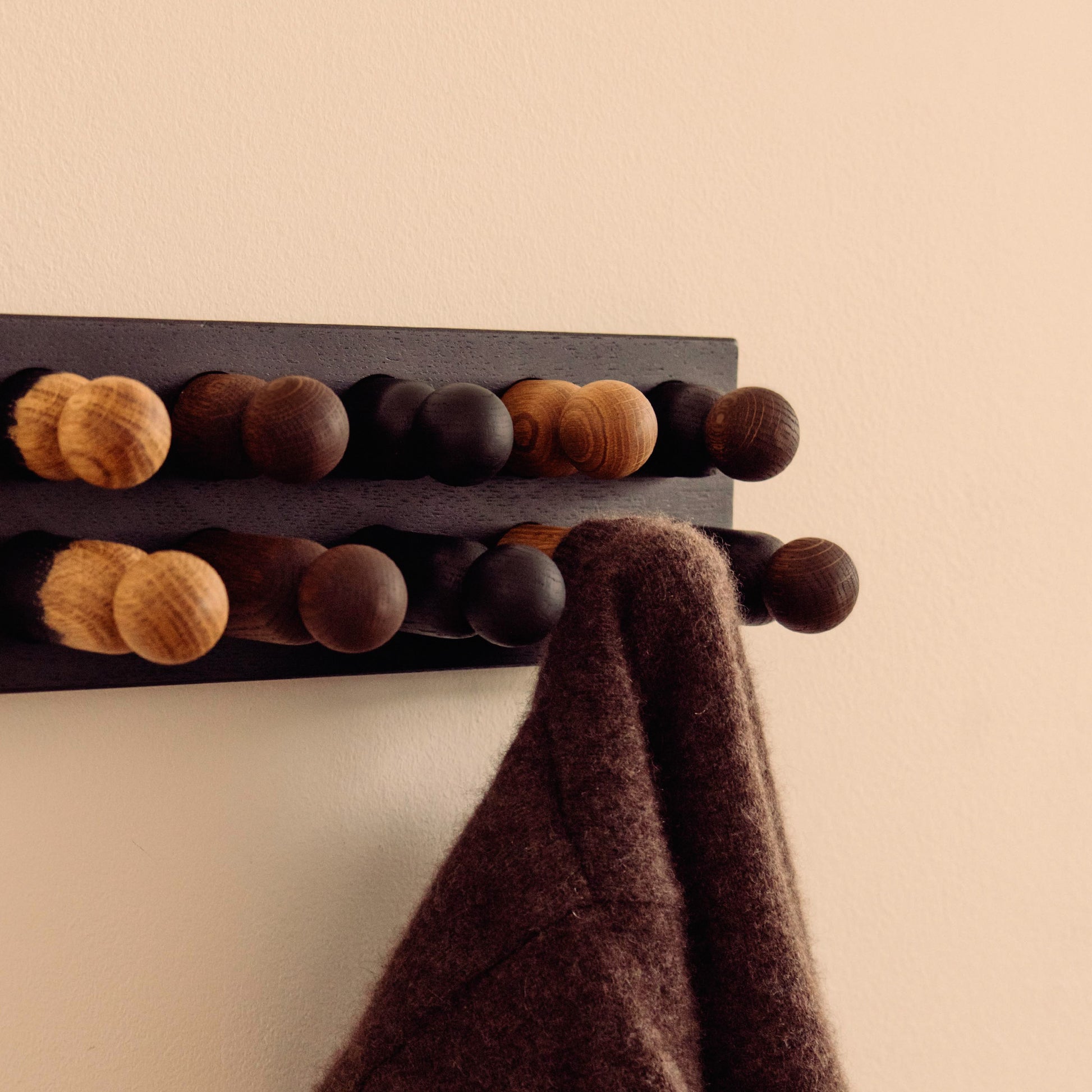 Wooden kids wall hooks in Black Oak with Mono Palette, shown in close-up detail as part of the Play & Hang coat rack by Woodsie Wonder.