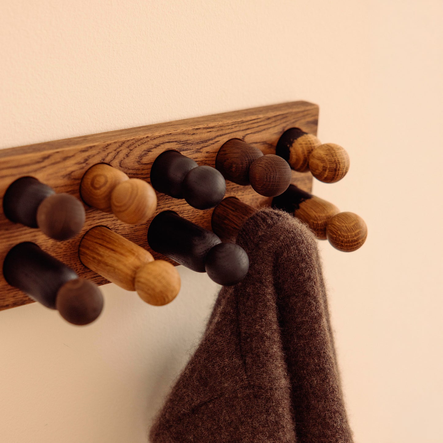 Wooden kids wall hooks in Brown Oak with Mono Palette, shown in close-up detail as part of the Play & Hang coat rack by Woodsie Wonder.
