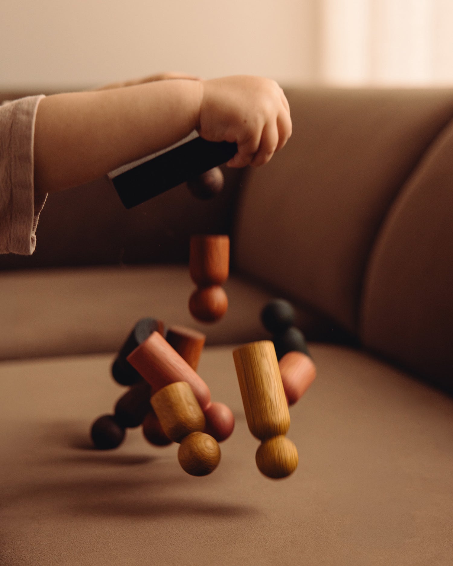 Child playing with the Woodsie Wonder Play & Hang wooden sorting toy and coat rack in Black Oak with the Earth Palette.