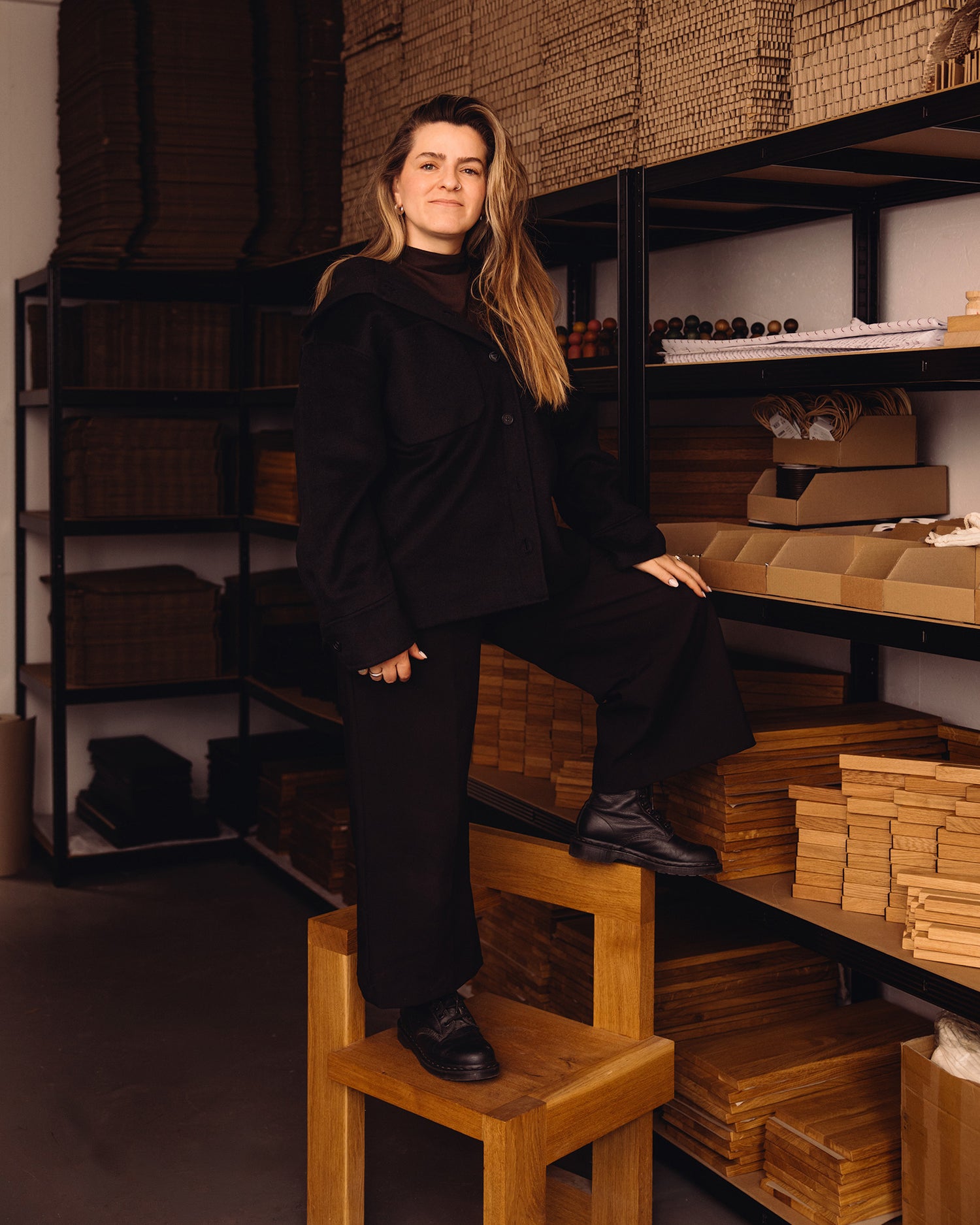 Woodsie Wonder founder Yonca Yilmaz standing in the Berlin workshop beside wooden product components.